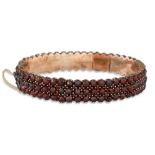 AN ANTIQUE BOHEMIAN GARNET BANGLE, safety chain