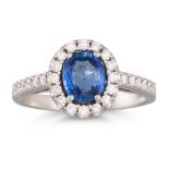 A SAPPHIRE AND DIAMOND CLUSTER RING, the oval sapphire to diamond surround and shoulders, in 18ct