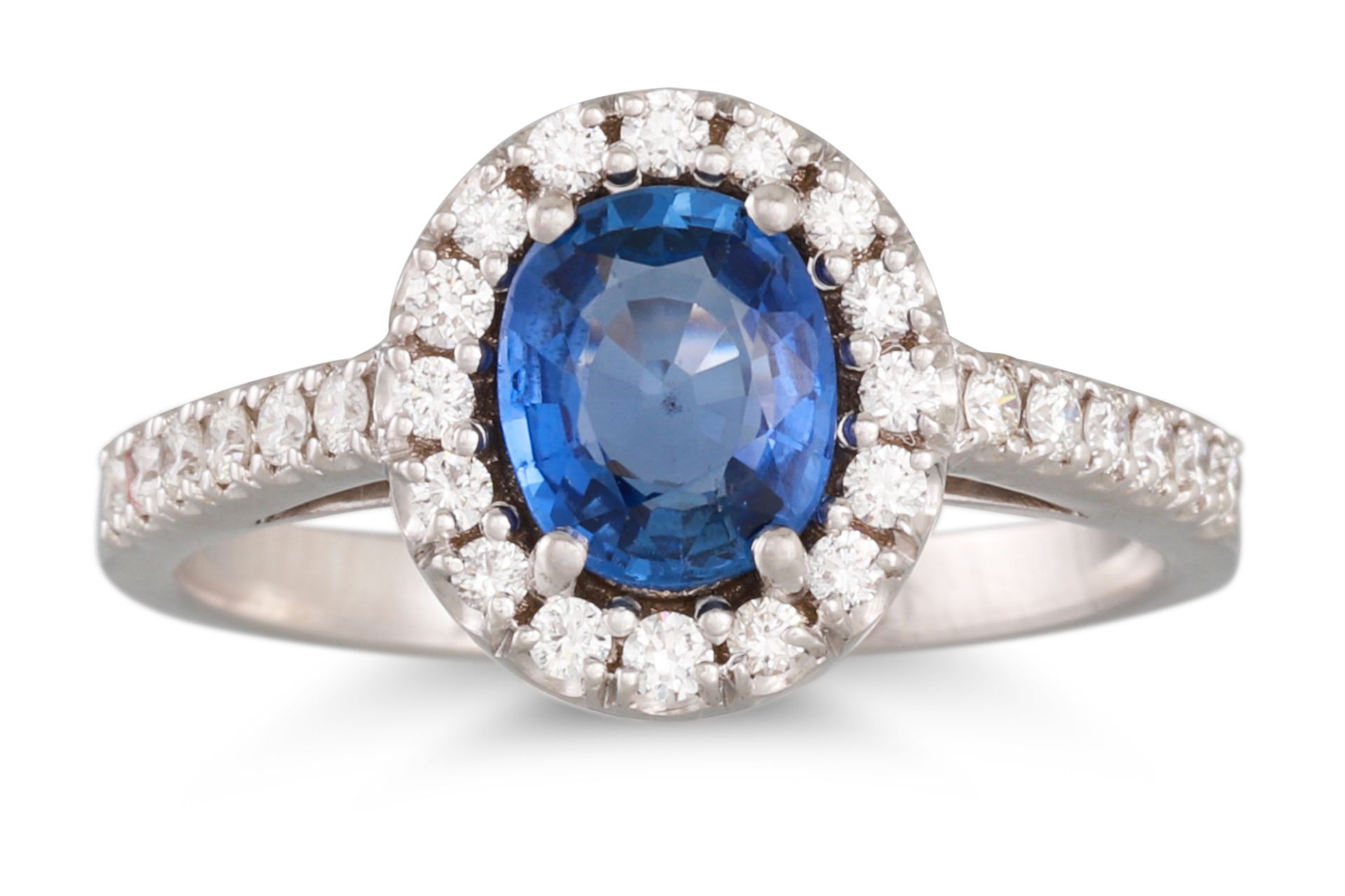 A SAPPHIRE AND DIAMOND CLUSTER RING, the oval sapphire to diamond surround and shoulders, in 18ct