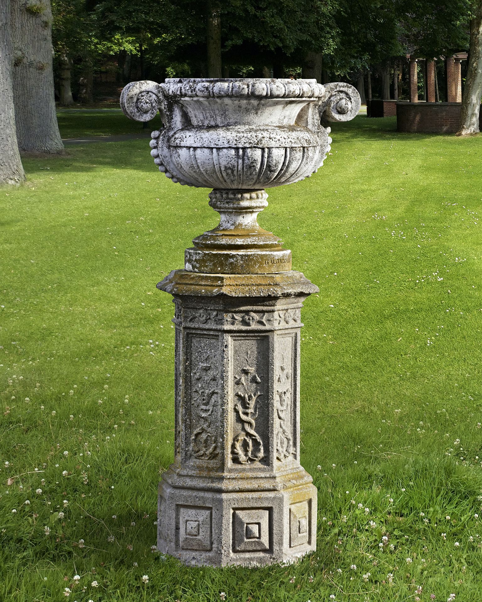 A LATE 19TH CENTURY COMPOSITION STONE VASE ON A COMPOSITION STONE DECORATED OCTAGONAL PEDESTAL