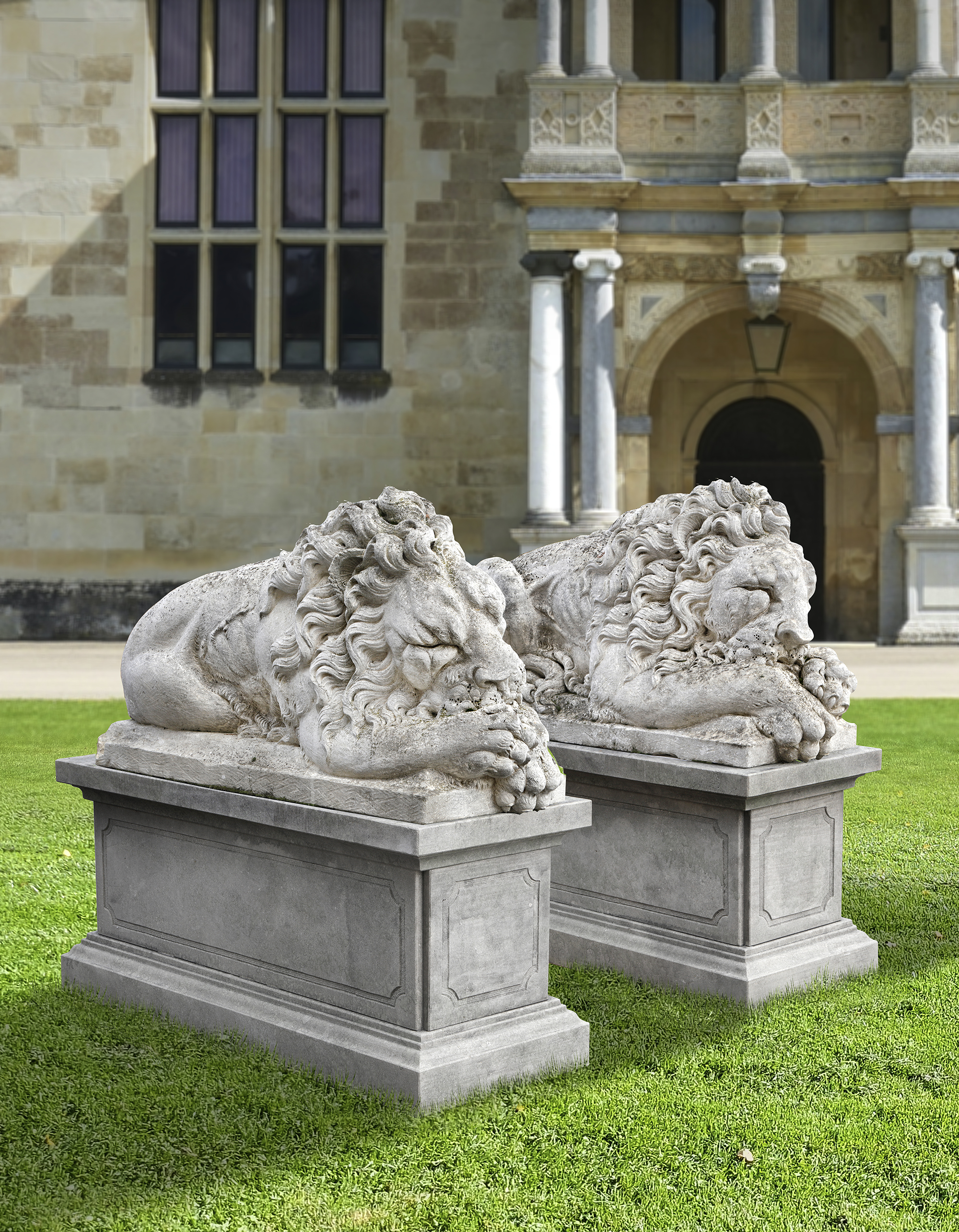 A PAIR OF SCULPTED LIMESTONE MODELS OF SLEEPING LIONS, MID 20TH CENTURY, LOOSELY AFTER THE MANNER OF