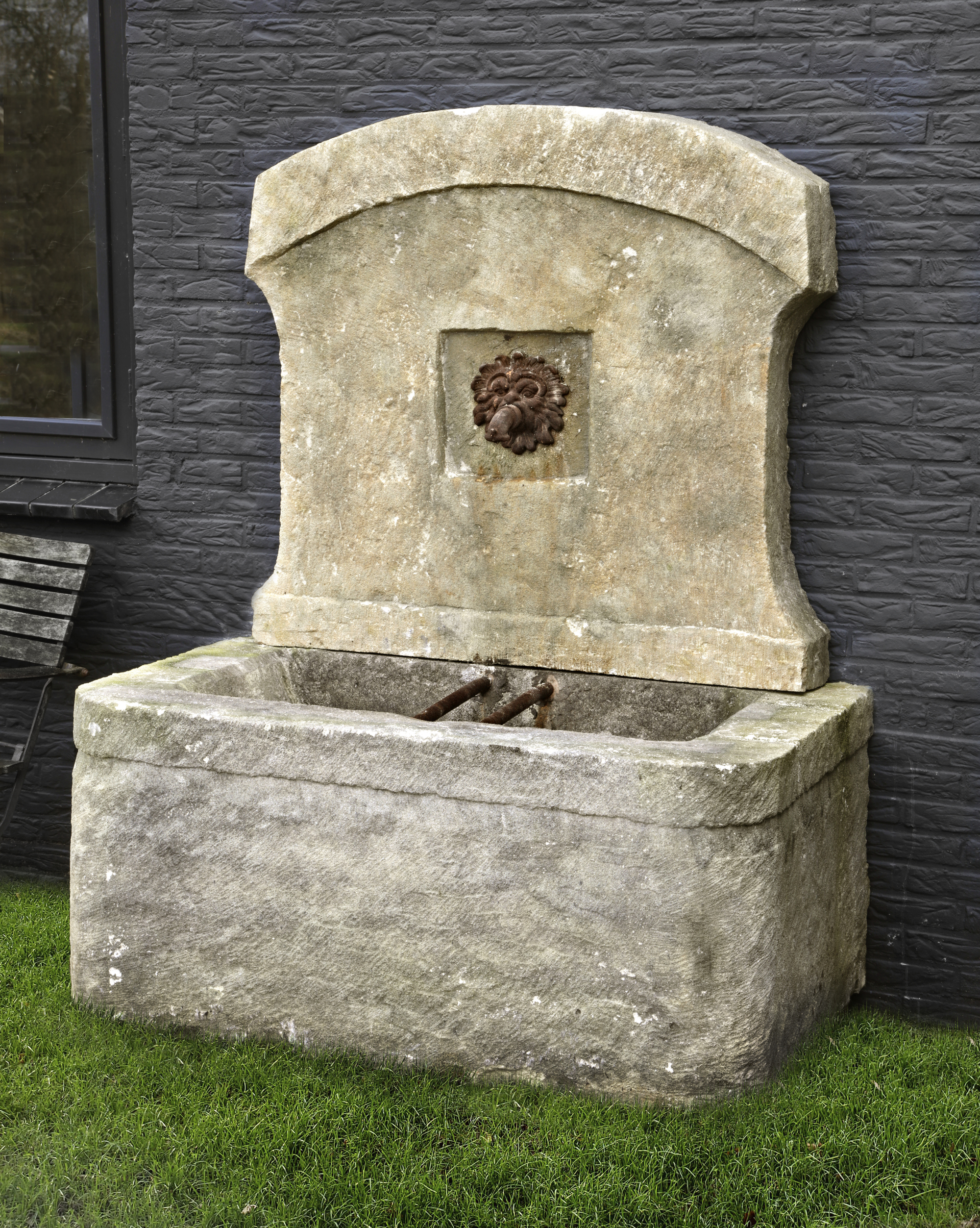 A SANDSTONE WALL FOUNTAIN INCORPORATING ASSOCIATED FRENCH 18TH CENTURY ELEMENTS