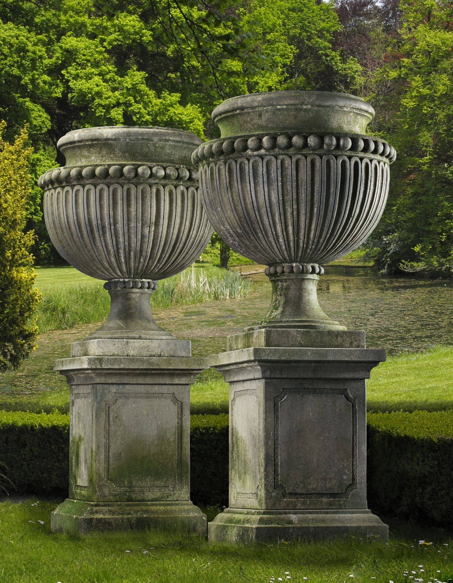 A PAIR OF LARGE AND IMPRESSIVE CARVED LIMESTONE GARDEN URNS ON PLINTHS IN IMPERIO TASTE, LATE 20TH C