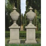 A PAIR OF CARVED LIMESTONE URNS ON PEDESTALS, LATE 20TH CENTURY, AFTER THE DESIGN BY WILLIAM KENT