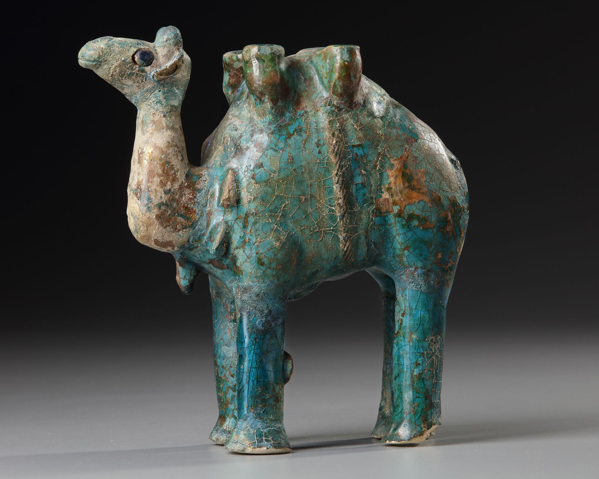 A TURQUOISE GLAZED POTTERY FIGURE OF A CAMEL, KASHAN, PERSIA, 11TH-12TH CENTURY