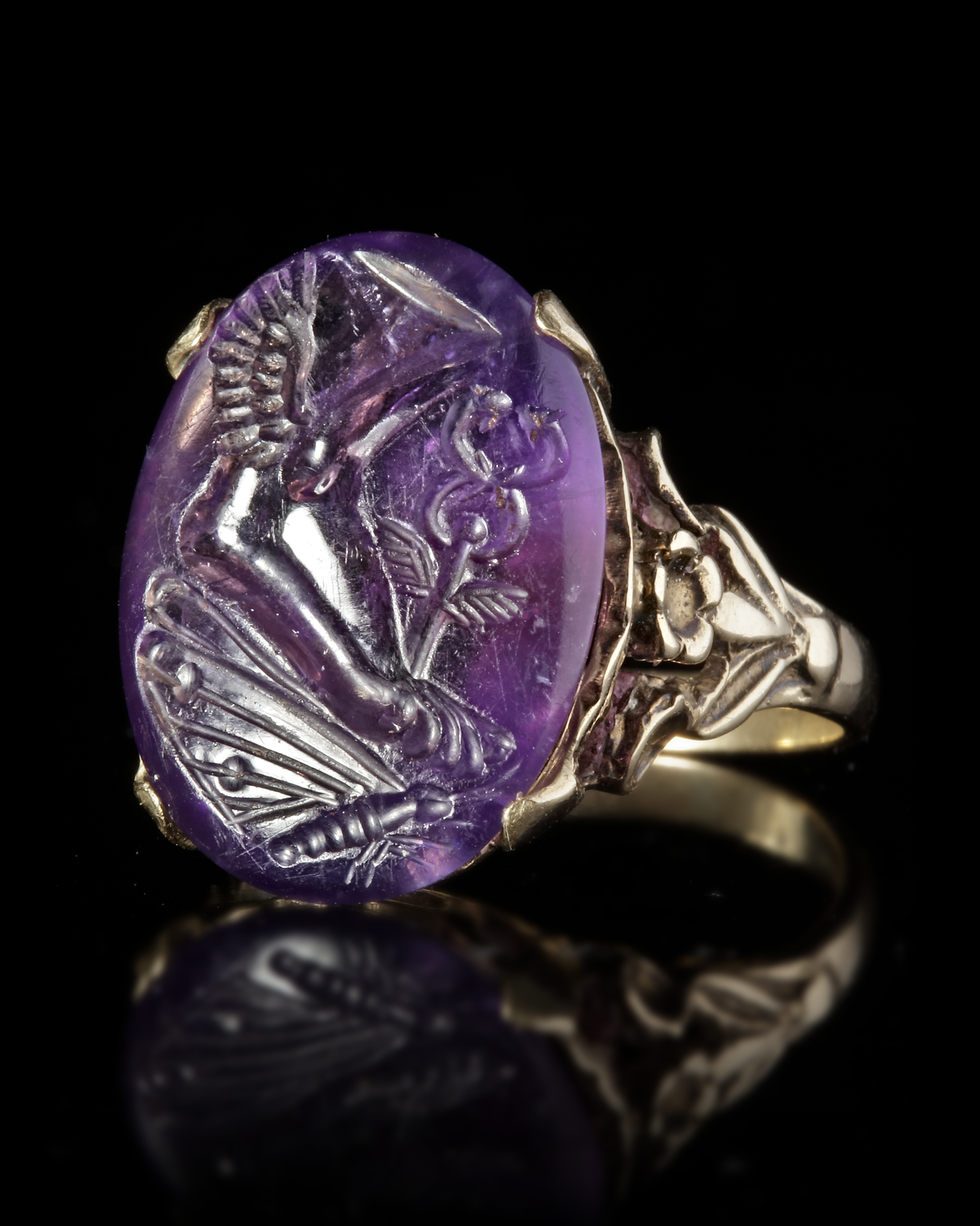 A ROMAN INTAGLIO IN AMETHYST WITH A FOOT OF MERCURY AND BUTTERFLY MOUNTED IN A 19TH CENTURY RING, IN