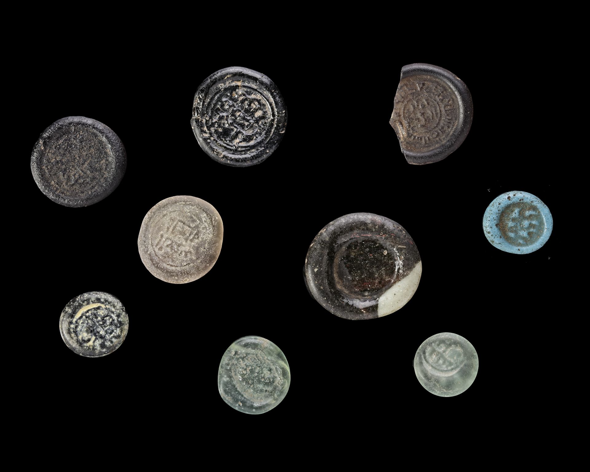 A GROUP OF NINE EARLY ISLAMIC GLASS WEIGHTS