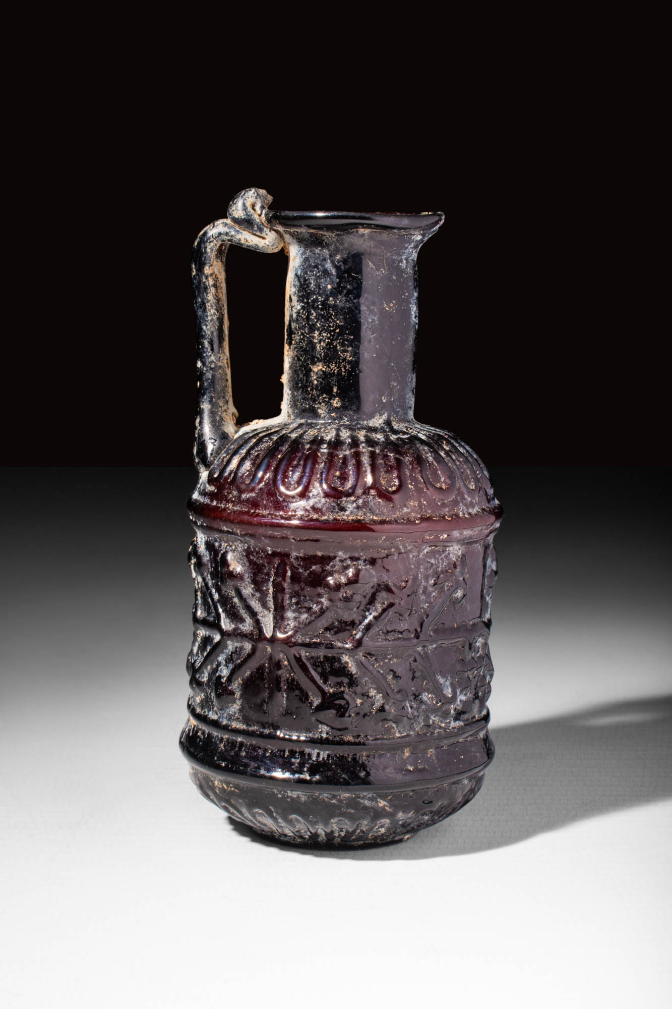 LATE ROMAN PURPLE GLASS BOTTLE DECORATED WITH MOULDED GEOMETRIC MOTIF - Image 2 of 5