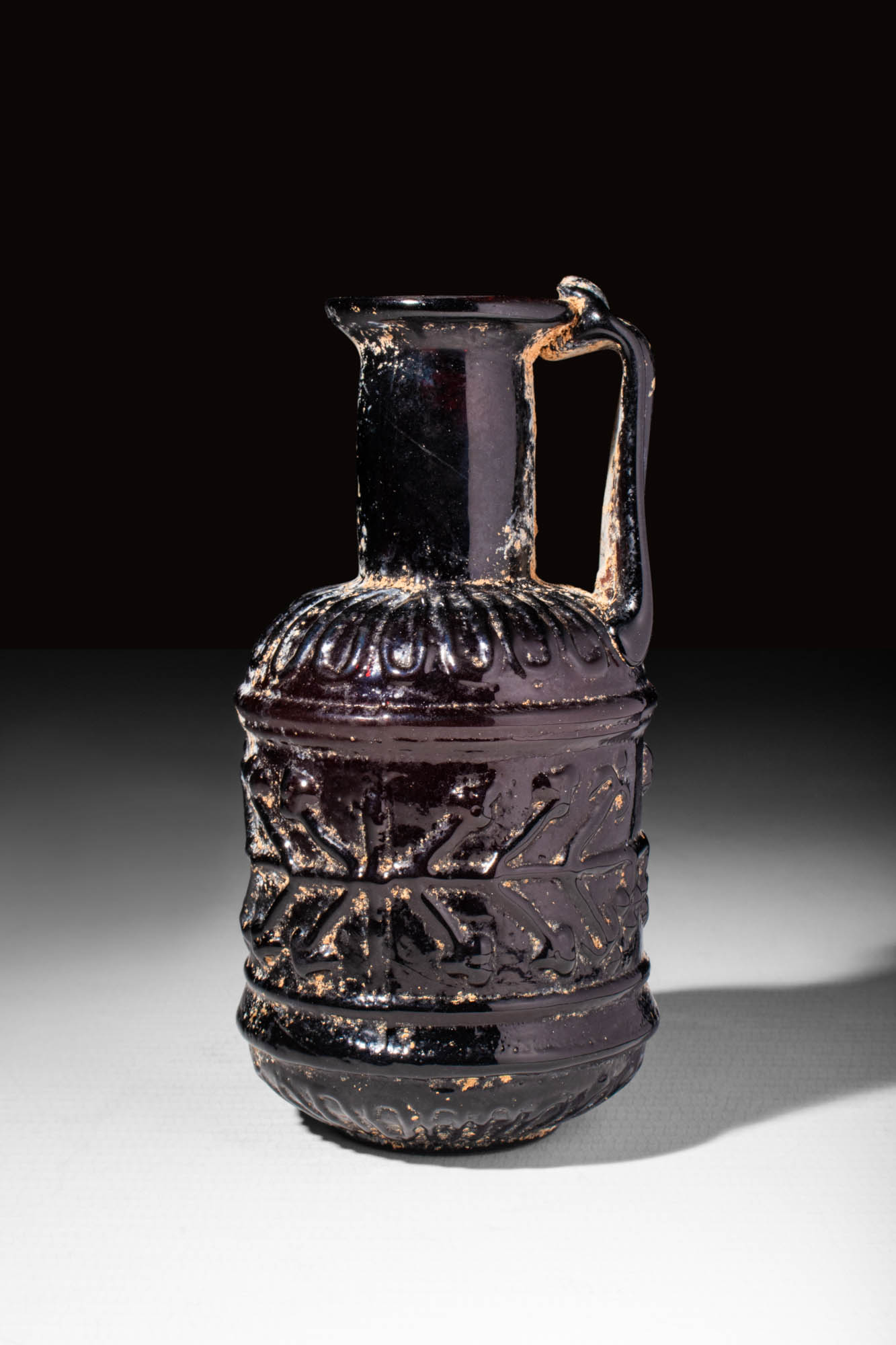 LATE ROMAN PURPLE GLASS BOTTLE DECORATED WITH MOULDED GEOMETRIC MOTIF - Image 3 of 5