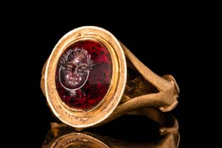 ROMAN GARNET INTAGLIO DEPICTING AN HEAD OF PUTTO IN GOLD RING