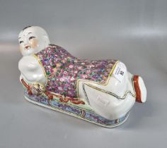 Chinese slip cast porcelain polychrome decorated pillow modelled as a reclining figure of a boy.