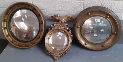 Two gilt framed convex mirrors, together with another modern gilded convex mirror with eagle