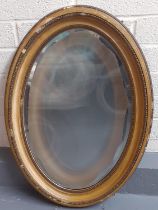 19th century gilded and bevelled mirror of oval form with moulded beadwork and similar designs. 90 x