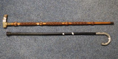 Ebonised walking cane with white metal handle together with an acorn carved walking stick with