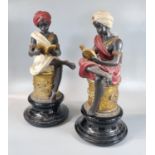 Pair of polychrome and gilt composition blackamoor figures of young boys sitting on pedestals,