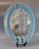 Early 20th Century blue glazed ceramic mirror, of oval form with relief decoration of cherubs with