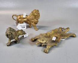 Gilt metal study of a male lion, together with a brass study of a male lion and a brass lion rug. (