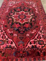 Full wool pile hand woven Persian carpet on a pink and red ground with large central medallion and