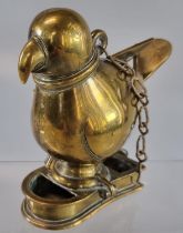 Unusual brass bird set on a shaped hollow base with spout, hinged where base joins the foot, with