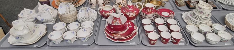 Four trays of 19th century tea ware, overall decorated on white and burgundy grounds with flowers