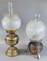 Two early 20th century double burner oil lamps, one standing on a copper reservoir with etched glass