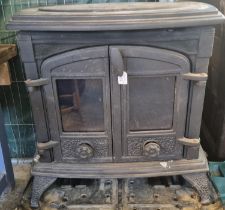 Large cast iron solid fuel stove with cooking surface above two glazed doors. 70cm wide approx. (B.