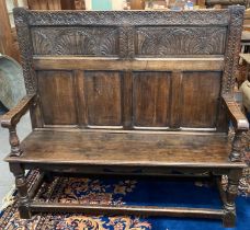 Reproduction 17th century style carved oak, panelled back hall settle with open arms and solid seat.