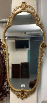 Modern gilt framed mirror of oval form decorated with pierced flowers and foliage. 95cm high approx.