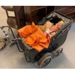 Vintage child's toy pram, the interior revealing three dolls and a vintage teddy bear in