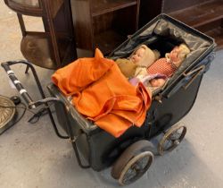 Vintage child's toy pram, the interior revealing three dolls and a vintage teddy bear in