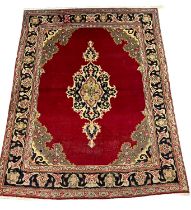 Red ground Persian Tabriz rug with central floral medallion and repeating multi-coloured floral