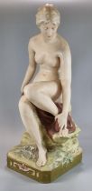 Early 20th century Royal Dux figure of a seated nude female bather, modelled on a rocky outcrop.