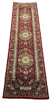 Red ground full pile Iranian Mashad runner, having three foliate and floral medallions with