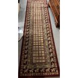Burgundy full pile wool runner with central square repeating geometric flowerhead design, the