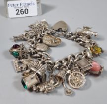Silver curb link charm bracelet with assorted charms including: bicycle lamp, Welsh dragon, Genie