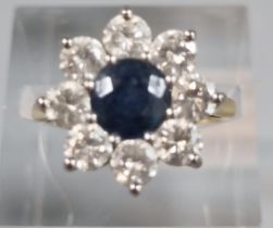 18ct gold eight stone diamond flower head ring with central sapphire stone. 5.5g approx. Size K. (