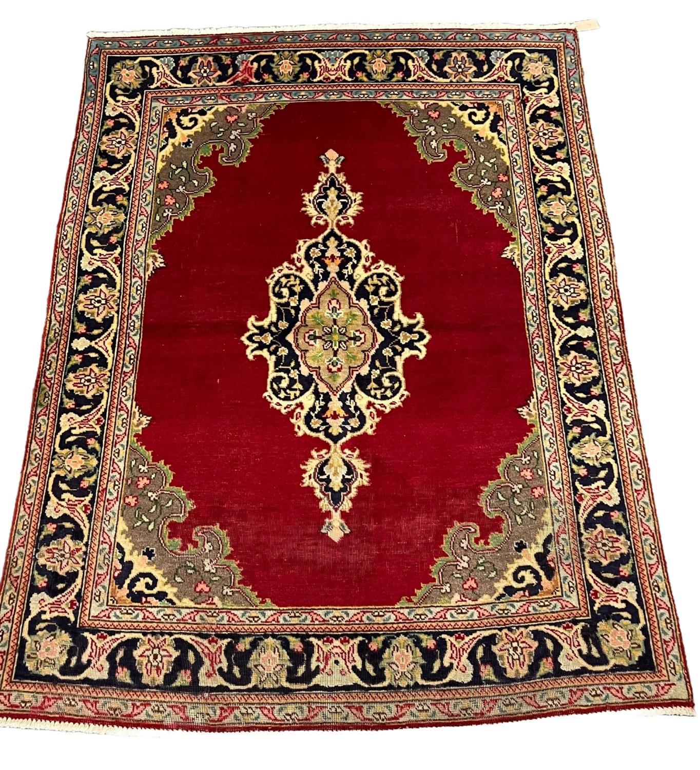 Red ground Persian Tabriz rug with central floral medallion and repeating multi-coloured floral