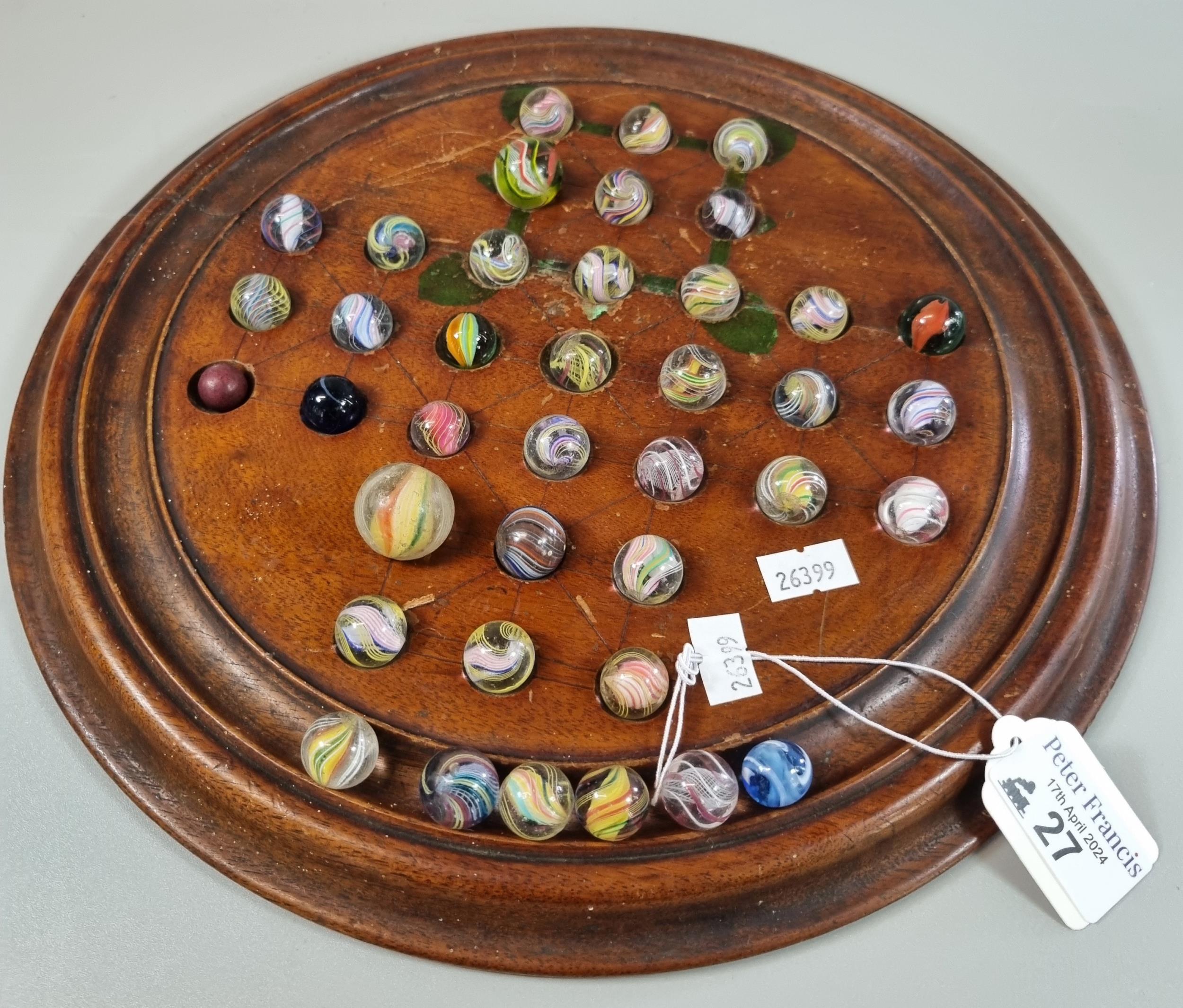 Turned wooden Solitaire board with a collection of mainly Victorian glass marbles. (B.P. 21% + VAT)