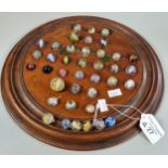Turned wooden Solitaire board with a collection of mainly Victorian glass marbles. (B.P. 21% + VAT)