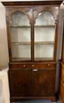 18th century style walnut and simulated walnut two door glazed bookcase of narrow proportions.