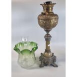 Early 20th century oil burner lamp having green and clear glass shade above a brass repoussé