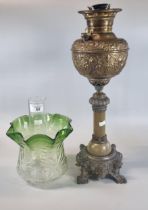 Early 20th century oil burner lamp having green and clear glass shade above a brass repoussé