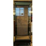 Tall ebonised glazed museum type display cabinet on a platform base with a swept cornice to the top,