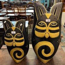 Two similar novelty carved and painted sculptures in the form of stylised cats. The tallest 61cm
