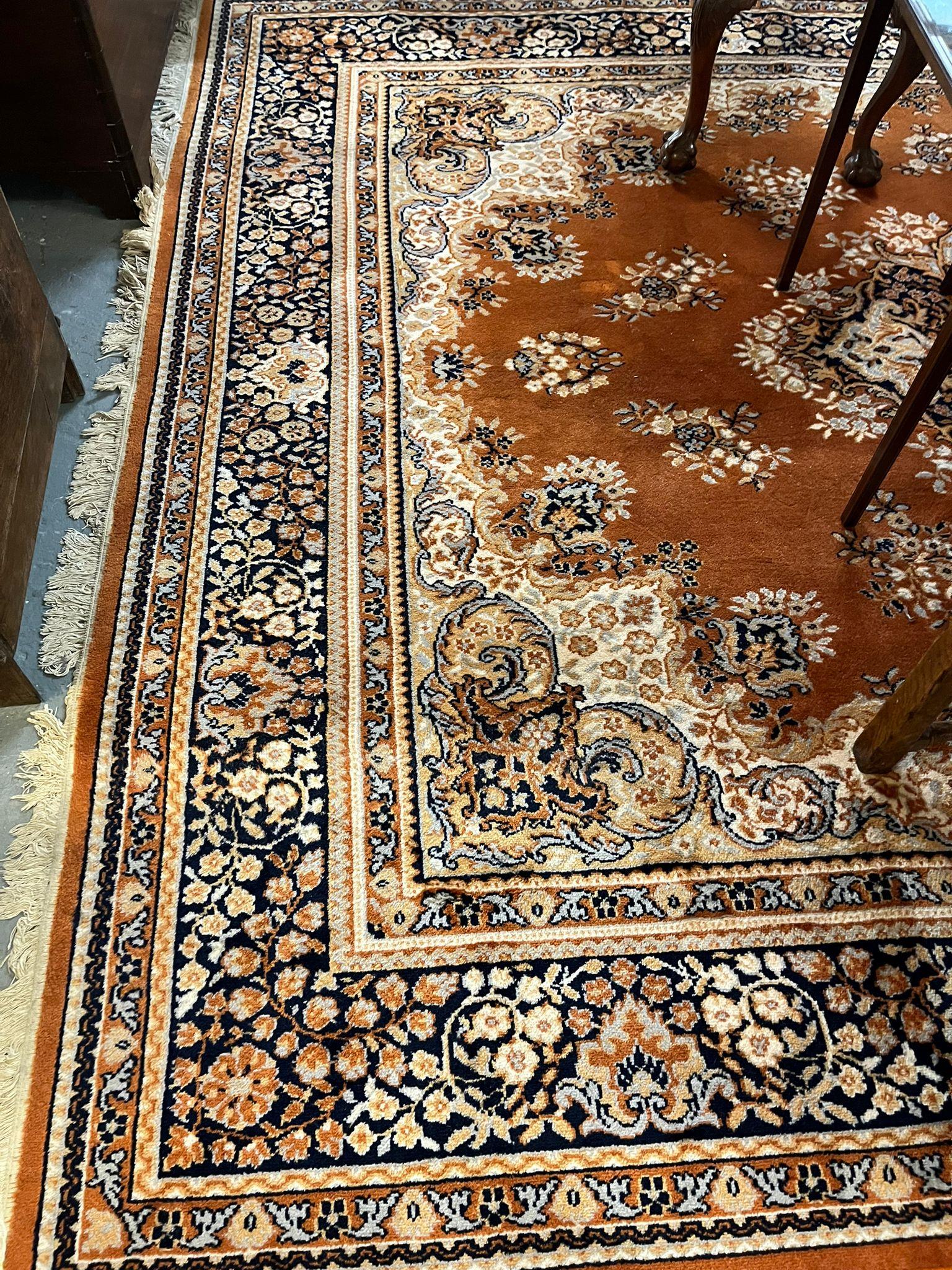 Large traditional design machine made orange ground carpet with overall foliate decoration.