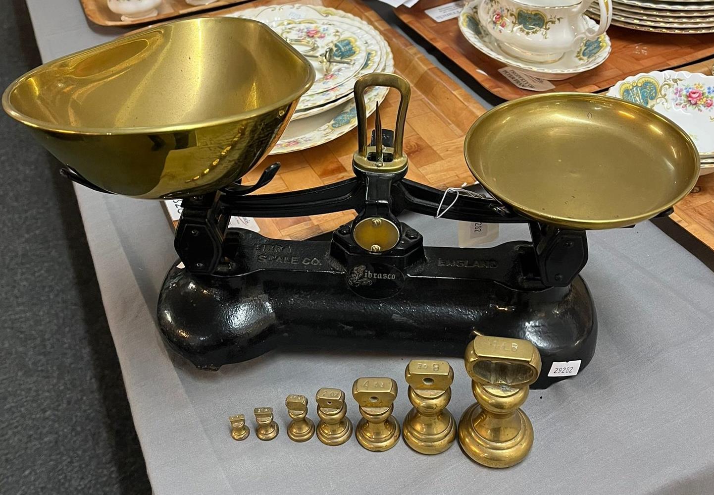 Set of black enamel kitchen scales with copper pans and graduated set of brass bell shaped