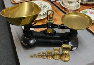 Set of black enamel kitchen scales with copper pans and graduated set of brass bell shaped