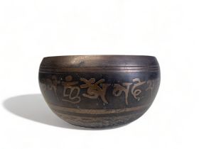 A VINTAGE TIBETAN SINGING BOWL. Stylised design & script to exterior, and relief symbols to