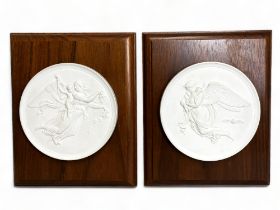 A pair of Royal Copenhagen bisque porcelain roundel plaques. Mounted on wood. Depicting 'Eneret, Day