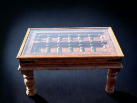 An Indian carved Teak 'Door' coffee table. With metal mounts and glass top.